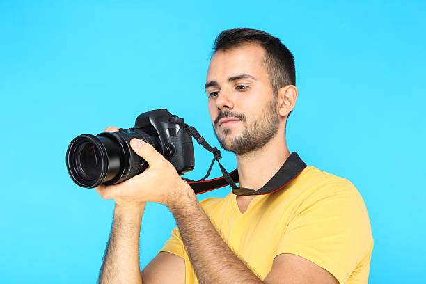 istock Young photographer with camera on blue background 2207469062
