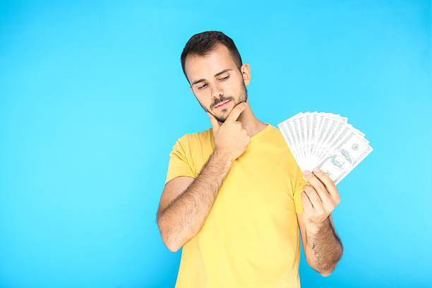 istock Young man holding dollar banknotes on blue background 2207470085