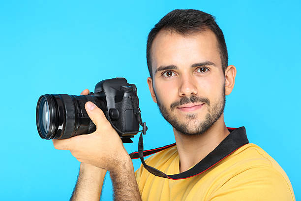 istock Young photographer with camera on blue background 2207470173