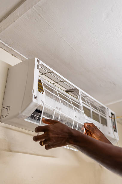 istock Home maintenance, Close-up, hands of African technician fixing air conditioner filter on a wall-mounted air conditioning unit. HVAC repair. 2207471283