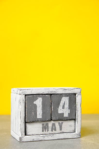 istock May 14 calendar made wooden cubes yellow background.With an empty space for your text. 2207472442