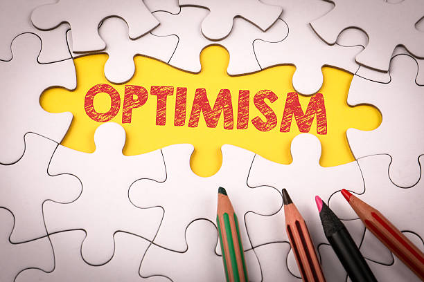 istock Puzzle Piece with Optimism Word Surrounded by Colored Pencils on White Background 2207479110