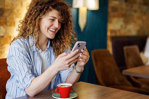 istock Curly woman texting at the restaurant while drinking coffee 2207483053