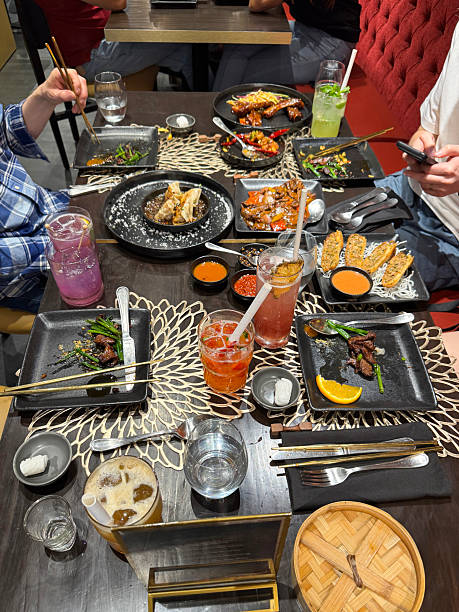 istock Image of using phone with chopsticks, enjoying chinese dumplings and spring rolls / overhead view of plates, delicious Asian food 2207484371