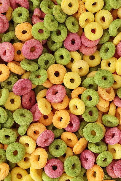 istock Full frame image of surface level of fruit flavoured, multi coloured breakfast cereal, crunchy O-shapes of cereal flours (wheat, oat, maize), sugar, yellow, red, green and orange, elevated view 2207489232