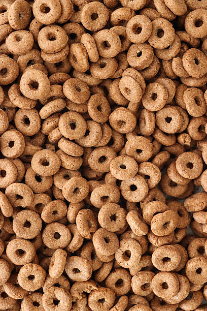 Stock photo showing close-up, elevated view of crunchy O-shapes of chocolate flavoured wheat breakfast cereal. This cereal is nice as a treat because although it does contain vitamins, minerals and fibre it also contains a high level of sugar.