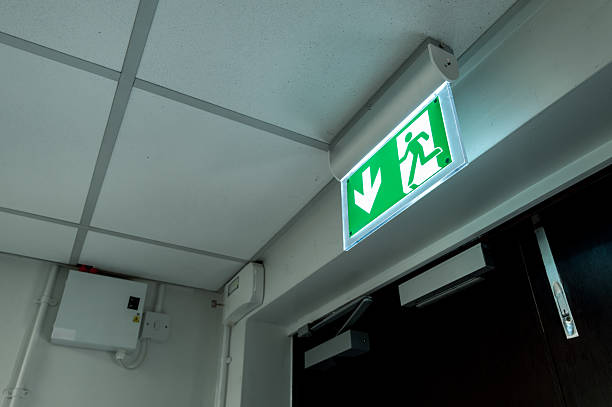 Industry-standard illuminated Fire Exit sign seen at the fire escape and emergency exit doors within a typical hospital. stock photo