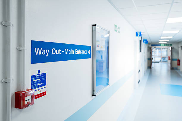 Shallow focus of a Way Out and Main Entrance sign seen within a typical NHS hospital in Britain. stock photo