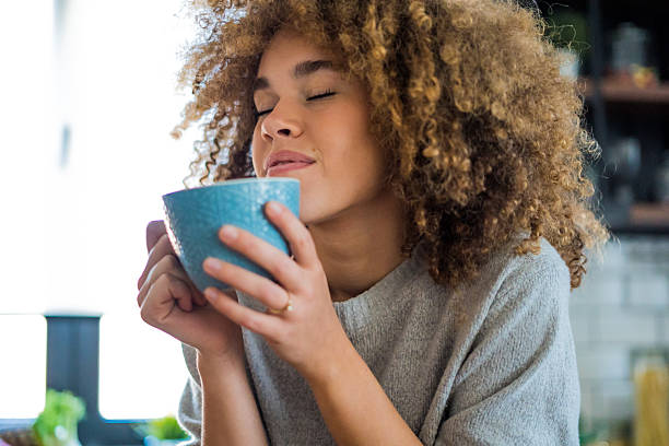 istock A young, beautiful woman with natural curls enjoys drinking coffee in a bright, modern kitchen. 2207490887