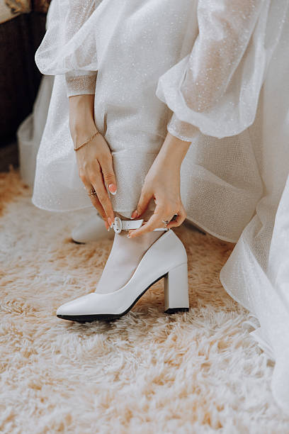 istock A woman in a white dress is getting ready to put on her wedding shoes 2207492425