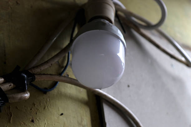 Photo of a light bulb with a cable attached to the wall of a house