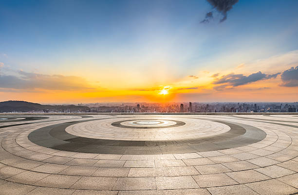 istock Empty floor with circular pattern and cityscape against a golden sunset 2207495402