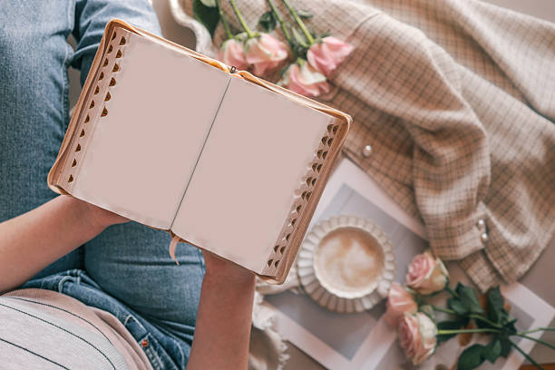 istock Person holding a blank open book while relaxing with coffee and roses. Soft pastel tones, cozy textures, and romantic atmosphere create a peaceful morning scene 2207512347