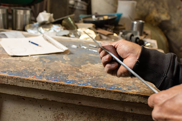 istock Shaping the Vision: Talented Blacksmith Sanding Metal Rod for Masterpiece 2207518891
