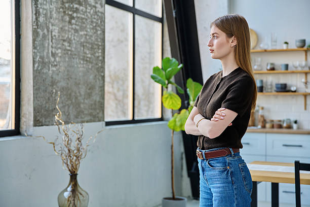 istock Serious confident young woman looking out the window, in home interior 2207527622