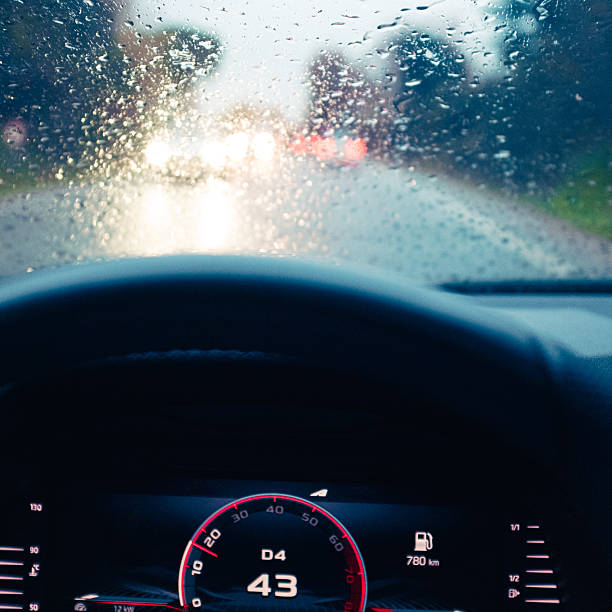 istock Windshield full of raindrops while driving on a road rainy weather at dusk driver's point of view 2207529545