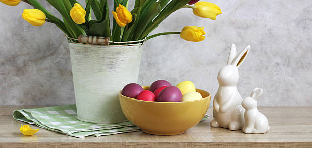istock Easter eggs in yellow bowl decorating home for easter celebration with yellow tulips and ceramic bunnies 2207530350