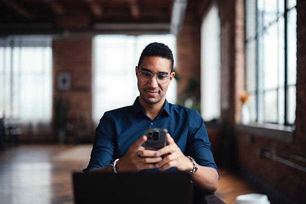 istock Professional Man Using Smartphone in a Bright Industrial Office Space 2207541586
