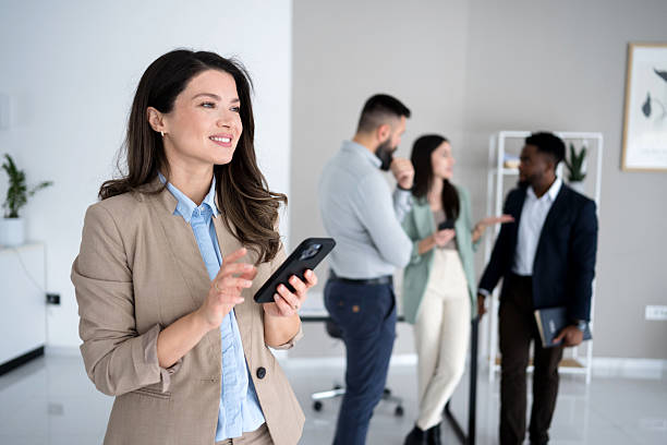 istock Mid adult businesswoman using her smart phone inside modern office 2207542588