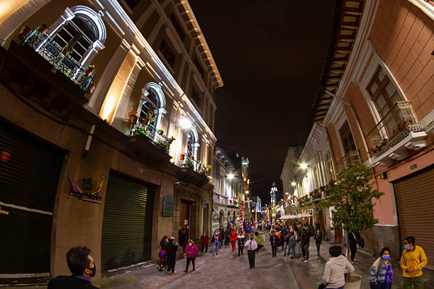 Quito, Pichincha, Ecuador - April 14, 2022: Quito's historic center streets are filled with people participating in the Holy Week procession, wearing masks and enjoying the colorful decorations and lights