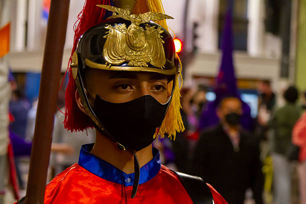 Quito, Pichincha, Ecuador - April 14, 2022: Young man dressed in a Roman soldier costume and wearing a protective face mask, participating in a vibrant procession during Holy Week celebrations in Quito, Ecuador