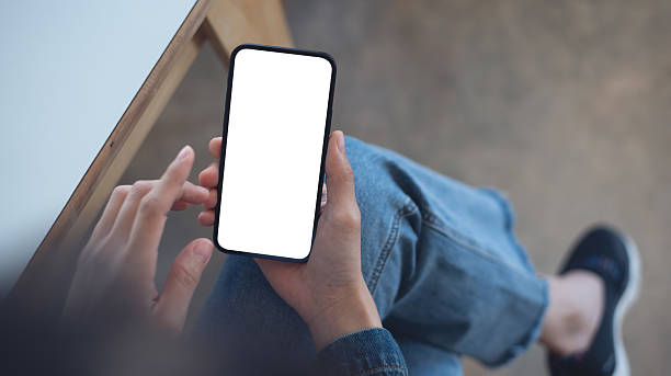 istock Cell phone white blank screen mockup, woman's hand holding mobile phone with blank screen and a cup of coffee in coffee shop, overhead shot, social media marketing design 2207556075