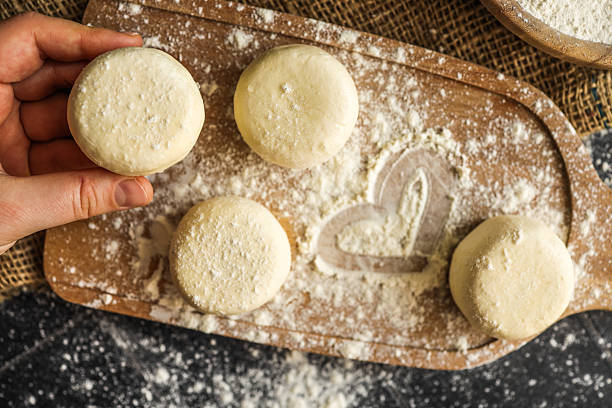 istock Close-up of a hand holding a raw dough round over a floured kitchen counter with baking tools in the background 2207563428