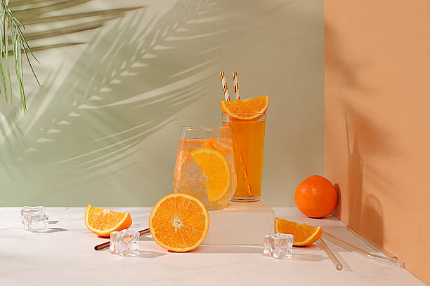 istock Orange juice and oranges on elegant kitchen table with long hard shadows. Modern still life with citrus fruits, minimal detox diet concept, summer vitamin drinks, selective focus, space for text 2207563499