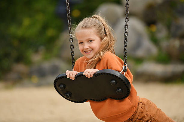 A girl riding on a swing in a park