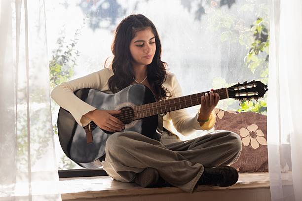 istock young latina woman sitting practicing guitar 2207581592