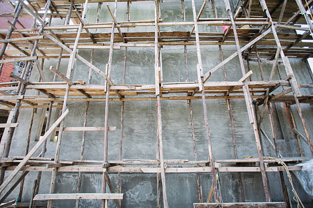Scaffolding surrounds a wooden building while it is under construction.
