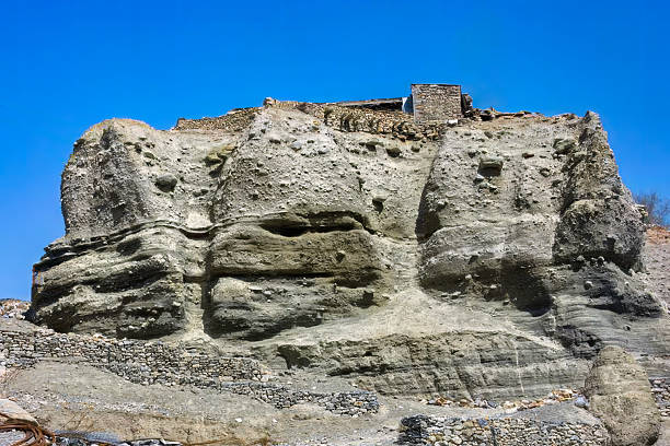 This captivating image showcases a naturally eroded rock formation in the Manang region of Nepal, along the renowned Tilicho Lake trek. Atop the massive rock structure, a small stone house, built by Sherpas, blends harmoniously with the rugged landscape.