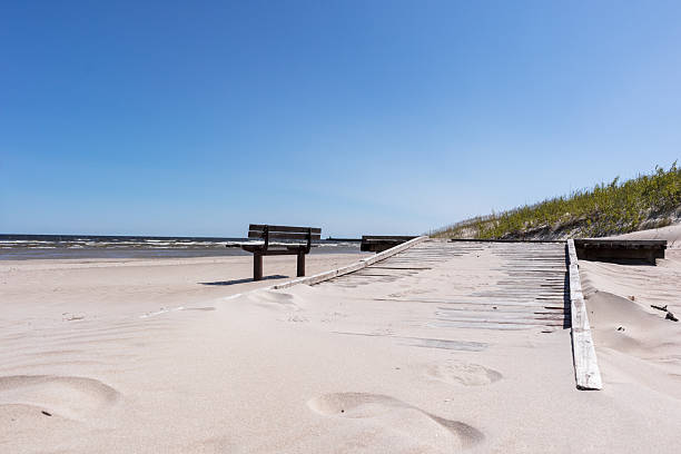 istock .beach with a bench and a concrete path leading to the sea. 2207586956