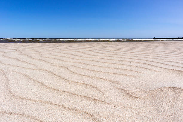 Sandy beach with wavy sand texture and the sea in the background.