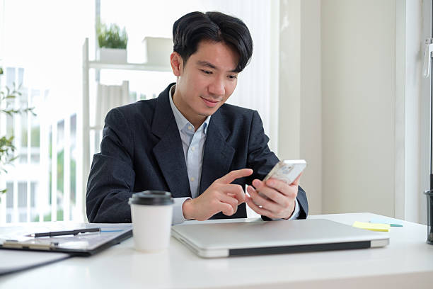 istock Cheerful business executive in a home office setting engages with his smartphone while multitasking. 2207589181