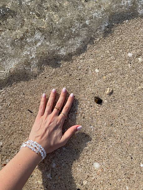 Sand falls from woman hands on sea summer background.