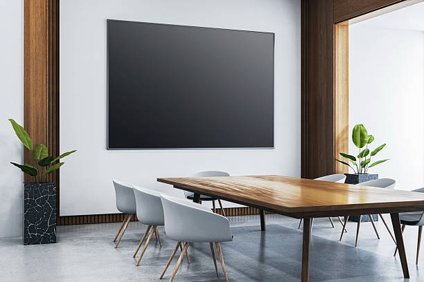 istock Modern conference room interior with blank black screen on the wall, wooden table, grey chairs, and minimalist decor in a clean office space. 3D Rendering 2207592269