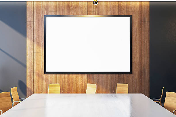 istock Modern conference room interior with blank white screen on wooden wall, surrounded by stylish chairs and clean table layout. 3D Rendering 2207592290