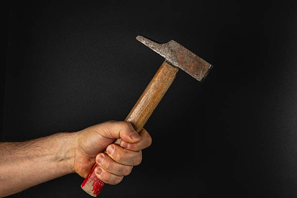 istock Hand holding a rusty hammer against a dark background 2207594384