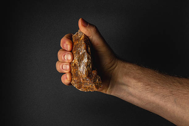 istock Strong hand gripping rough stone in a dark setting 2207594502