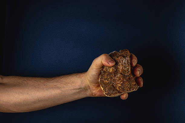 istock Strong hand holding a rock against dark background 2207594881