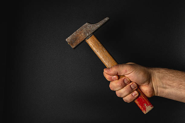 istock Hand holding a hammer against a dark background 2207595461