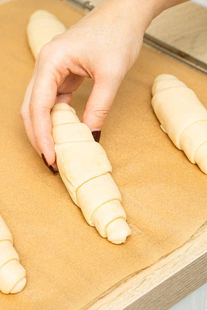 istock woman placing croissant on baking sheet, vertical photo 2207602206