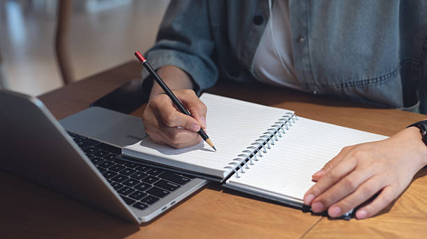 istock Business planning, E learning concept. Casual business woman writing on notebook and working on laptop computer in office. Student studying online course via laptop and noting on notepad. 2207609053
