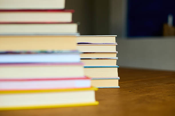 Stacked books on a wooden surface with a blurred background in a cozy reading space