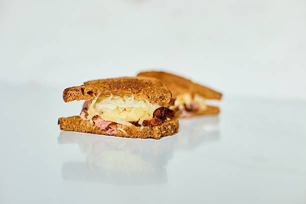 Delicious Reuben sandwich featuring toasted rye bread, tender corned beef, sauerkraut, and melted cheese served on a white background