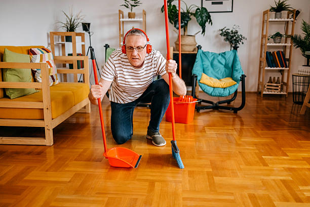 istock Mid adult man cleaning his home using broom 2207612135