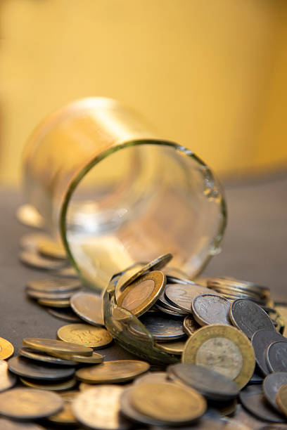 istock Shattered Glass Jar with Scattered Currency Coins Representing Financial Hardship 2207612904