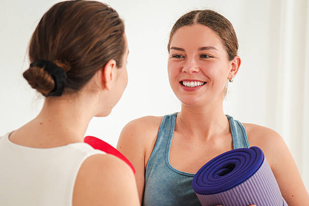 istock Two enthusiastic women engaging in a lively conversation while holding yoga mats and discussing fitness and wellness strategies for a healthier lifestyle and balanced routine 2207614037