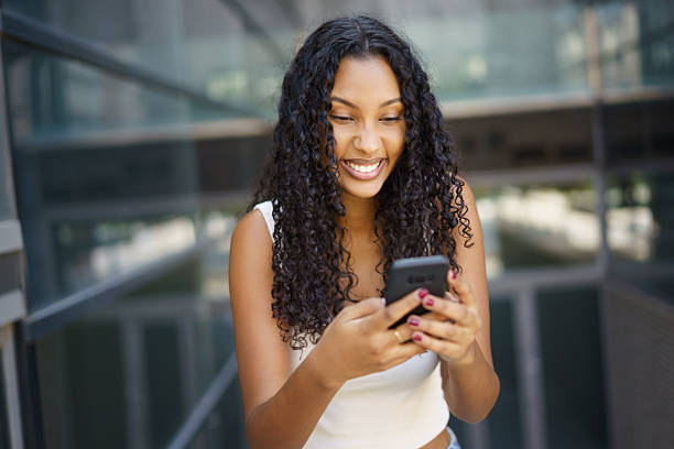 istock A Young Woman Happily Smiling While Using Her Smartphone Outdoors in Bright Daylight 2207617720